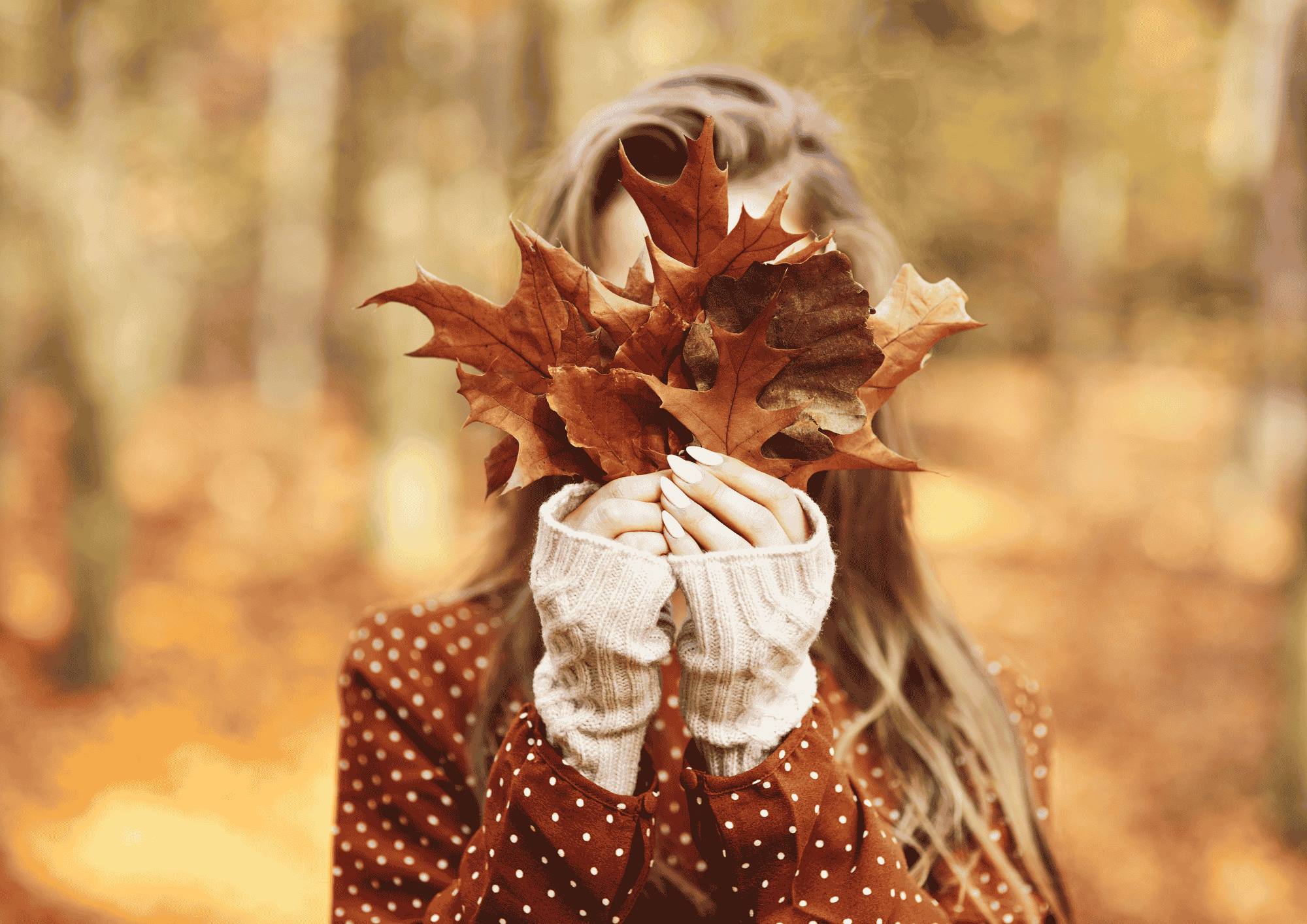 Vrouw met herfstbladeren. 8 tips voor een gezonde, stralende huid in de herfst.