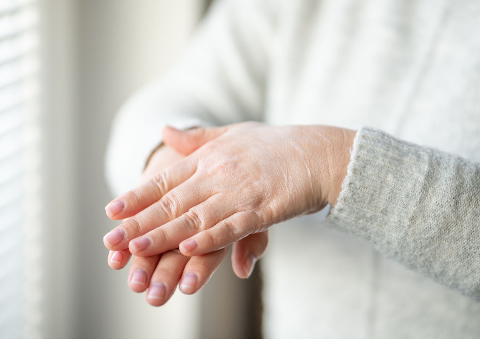 Vrouw die haar handen verzorgt met een voedende handcrème.